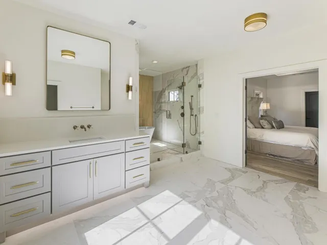 a bathroom with a sink a toilet a mirror and shower