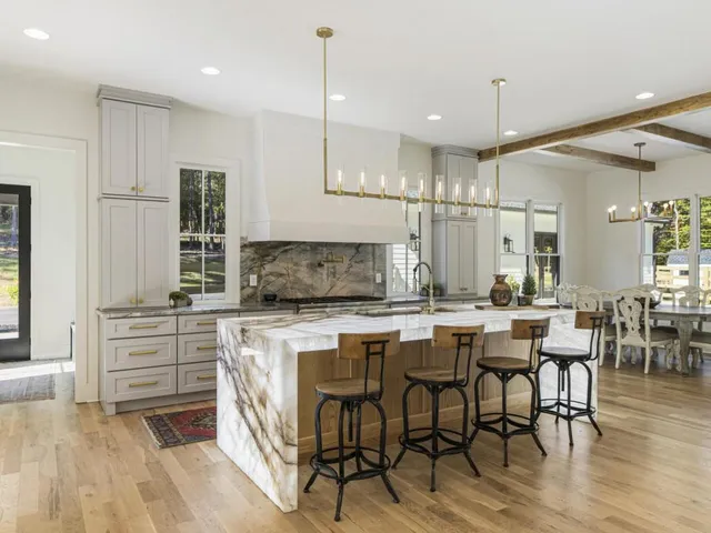 a kitchen with kitchen island granite countertop a table chairs sink and cabinets