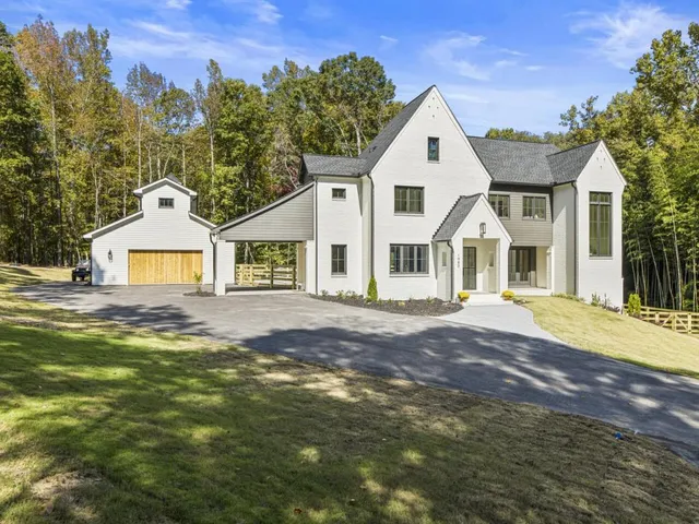 a view of a white house with a yard and large trees