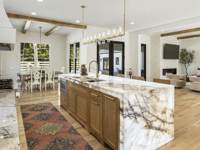 a kitchen with stainless steel appliances granite countertop a white cabinets a stove and a chandelier