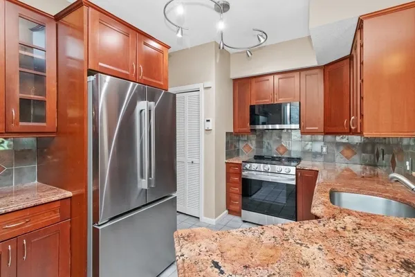 a kitchen with stainless steel appliances granite countertop a refrigerator a stove and a sink with cabinets