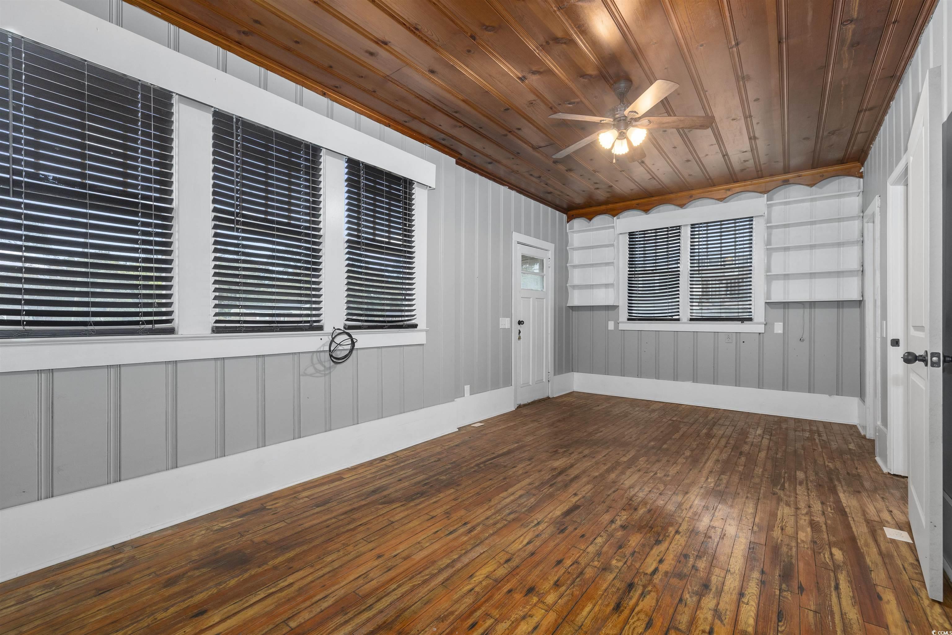 205 South Nichols Street Nichols, SC 29581 - Photo 19 of 27 Unfurnished room featuring ceiling fan, crown molding, wooden ceiling, dark hardwood / wood-style floors, and wood walls
