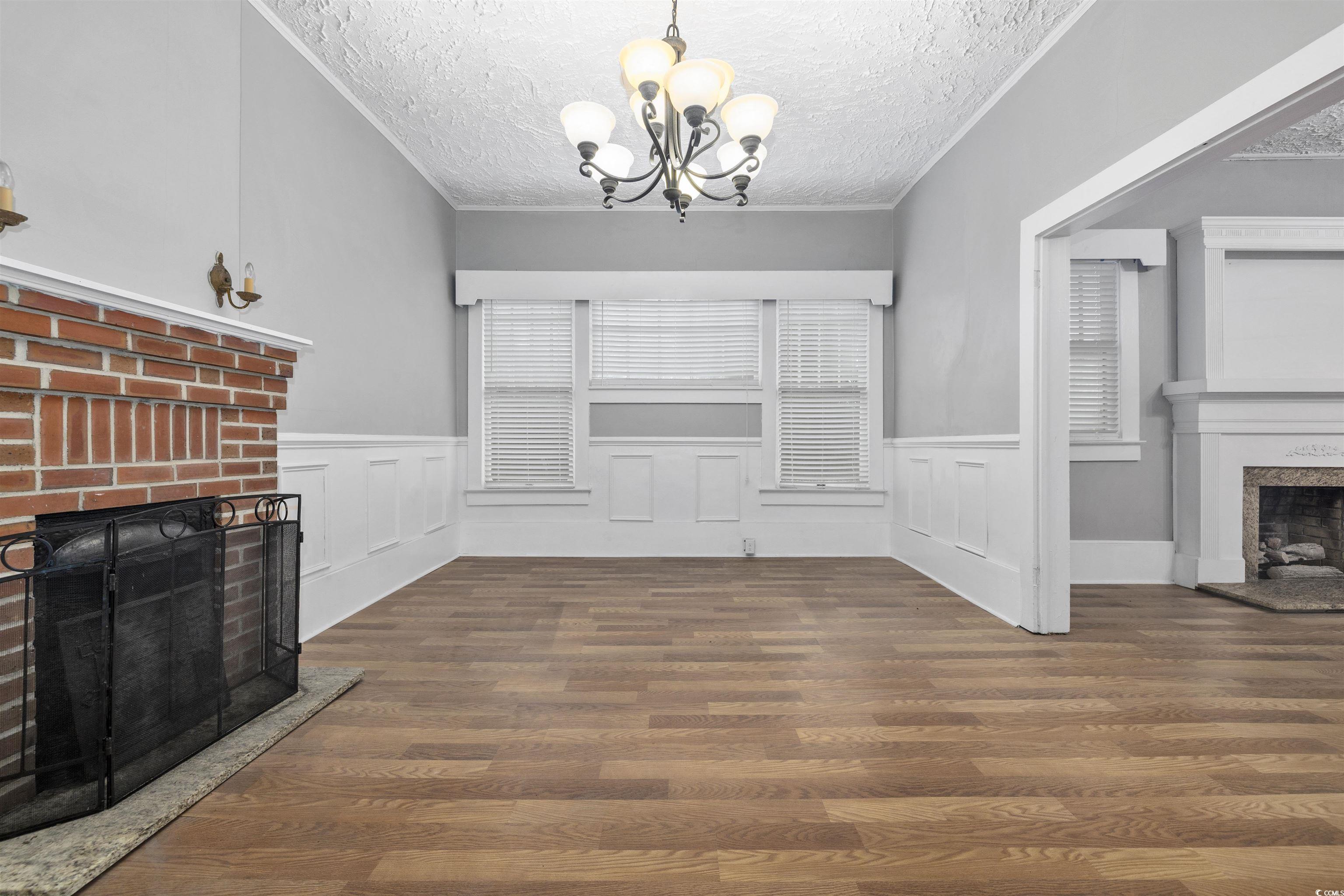 205 South Nichols Street Nichols, SC 29581 - Photo 6 of 27 Unfurnished living room with a textured ceiling, a chandelier, dark wood-type flooring, and a brick fireplace