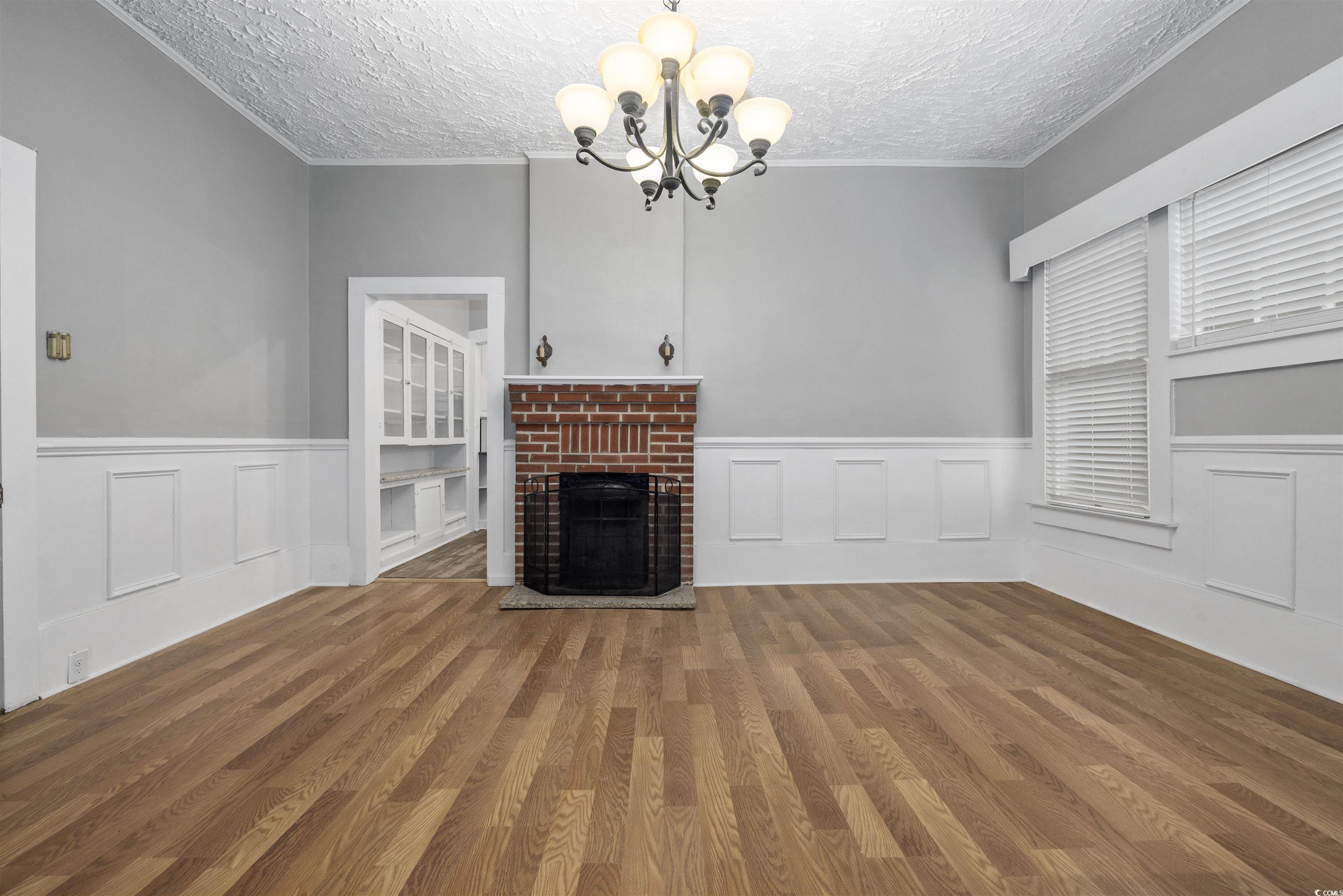 205 South Nichols Street Nichols, SC 29581 - Photo 7 of 27 Unfurnished living room featuring a chandelier, wood-type flooring, and a textured ceiling