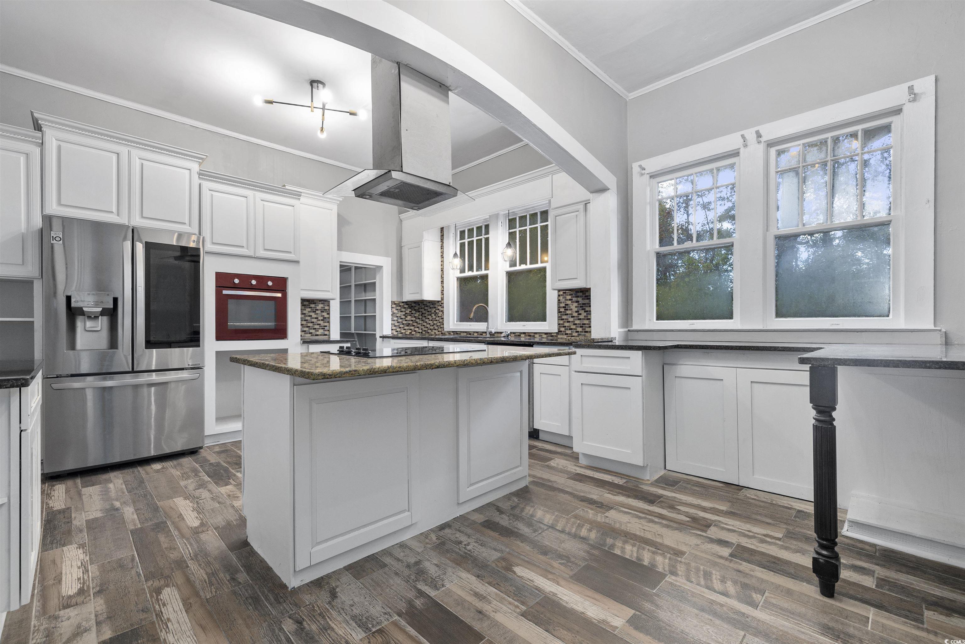 205 South Nichols Street Nichols, SC 29581 - Photo 8 of 27 Kitchen with black appliances, dark hardwood / wood-style floors, white cabinetry, and island exhaust hood