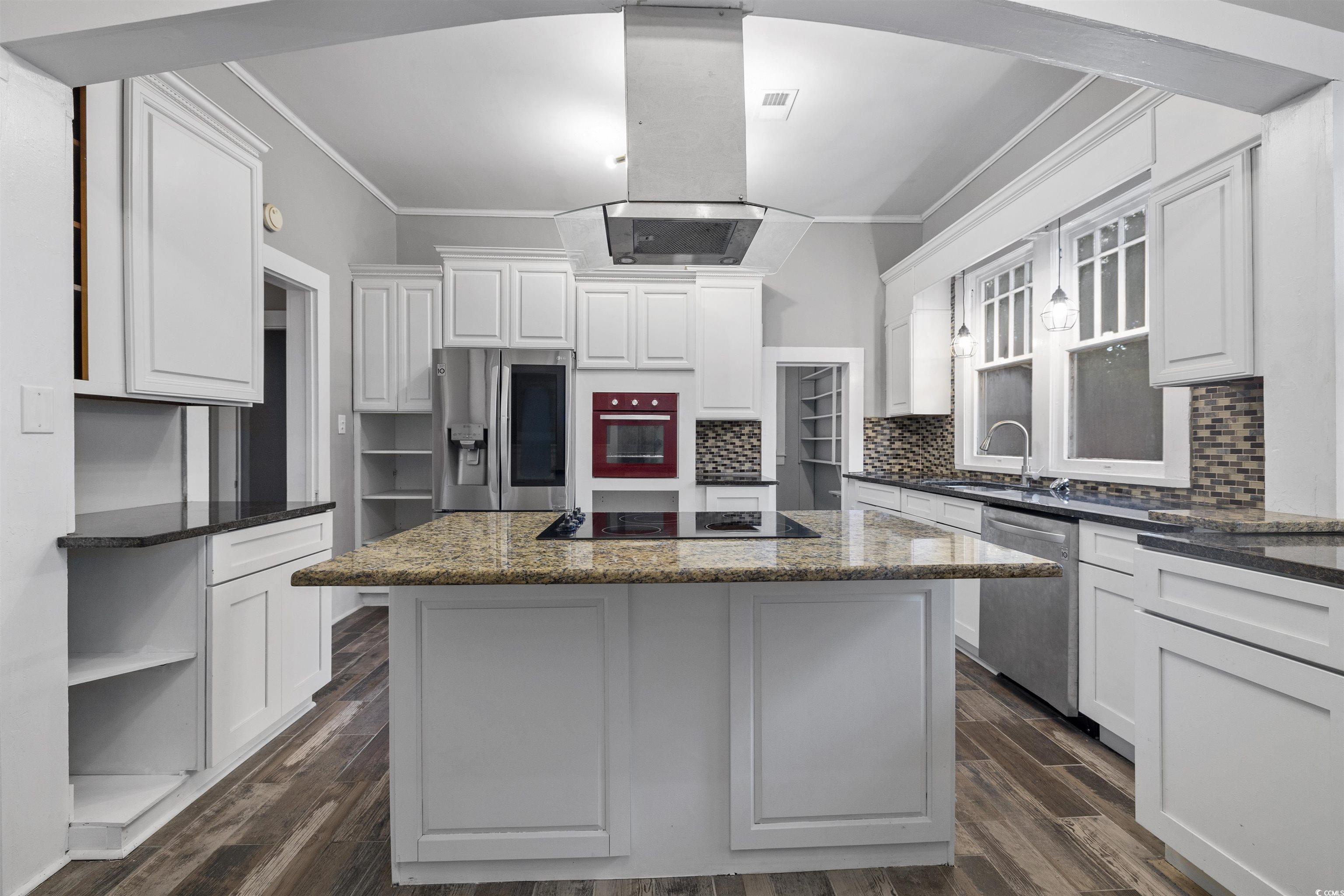 205 South Nichols Street Nichols, SC 29581 - Photo 10 of 27 Kitchen with appliances with stainless steel finishes, dark stone counters, dark wood-type flooring, white cabinets, and a kitchen island
