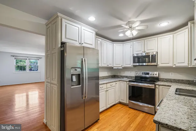 a kitchen with stainless steel appliances granite countertop a refrigerator and a stove top oven