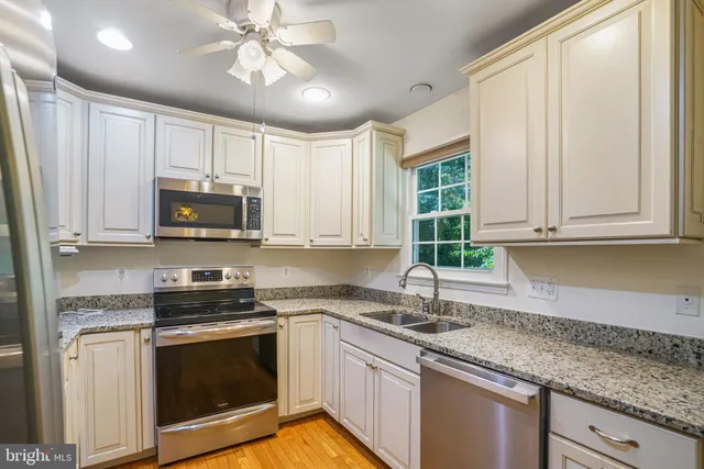 a kitchen with stainless steel appliances granite countertop white cabinets granite counter tops and a window