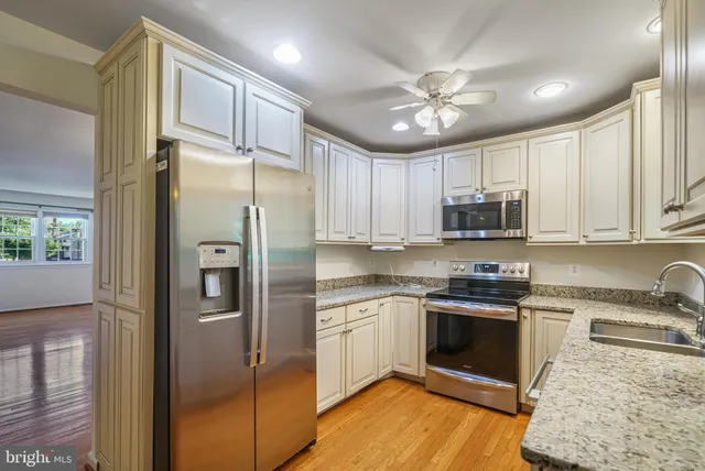a kitchen with stainless steel appliances granite countertop a refrigerator a sink a stove with cabinets