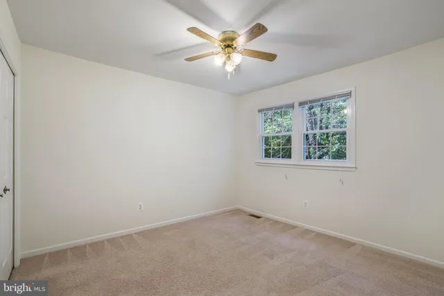 an empty room with a window and a ceiling fan