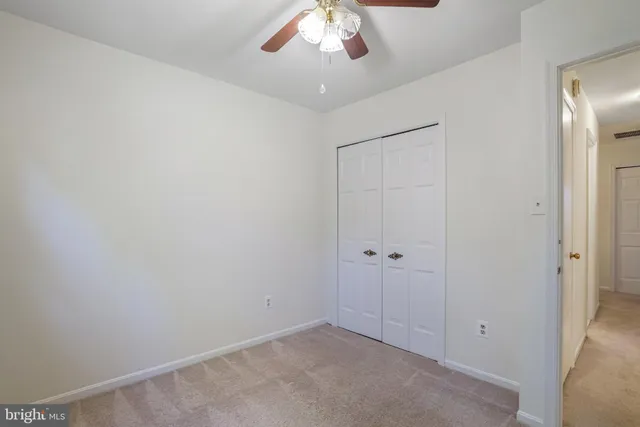 an empty room with a chandelier fan and closet area