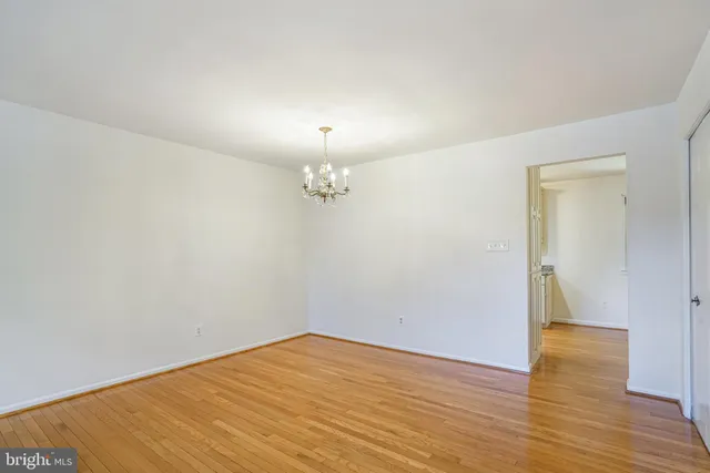 an empty room with wooden floor and chandelier fan