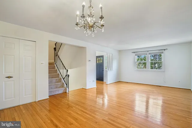 a view of an empty room with wooden floor and staircase