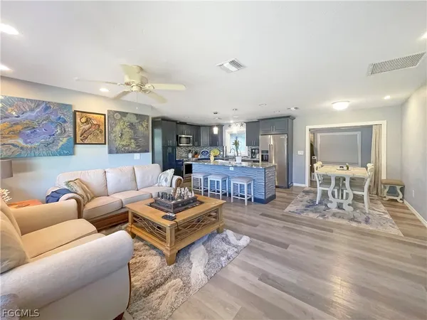 a living room with furniture kitchen view and a wooden floor
