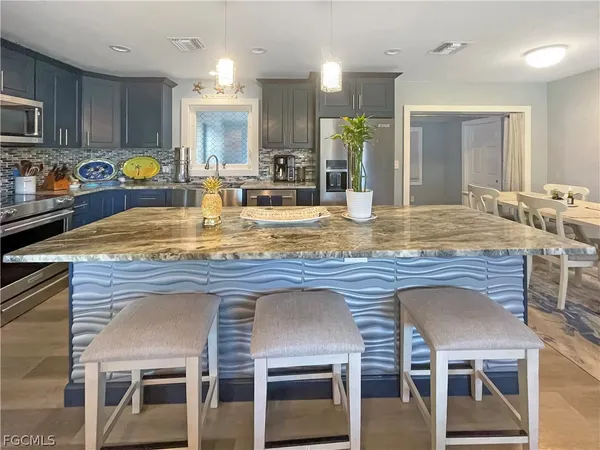 a kitchen with kitchen island granite countertop wooden cabinets and a refrigerator