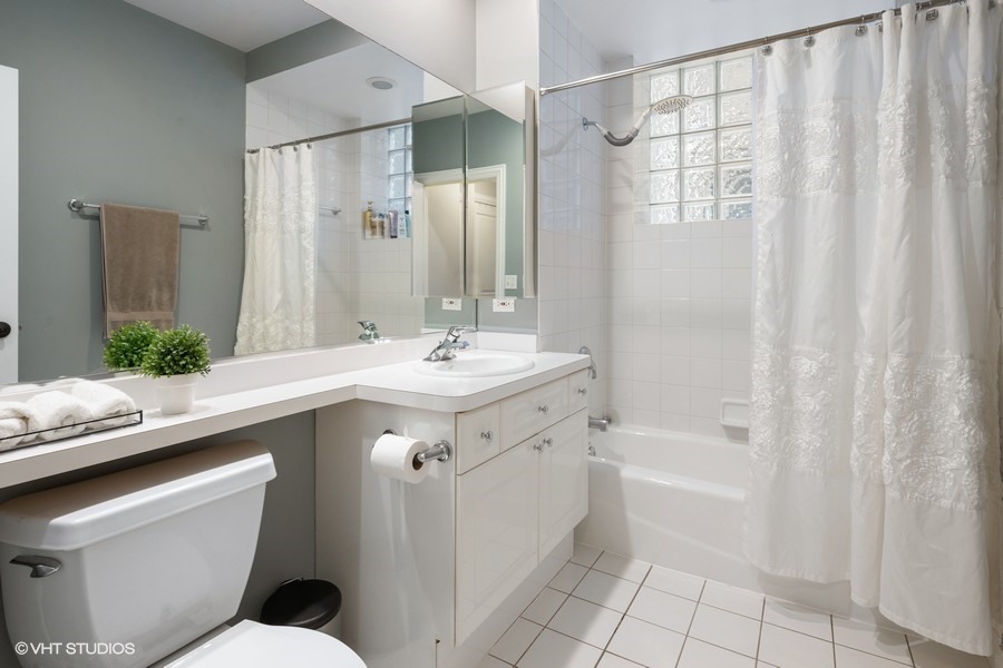 1316 West Fletcher Street, Unit 1E Chicago, IL 60657 - Photo 12 of 13 a bathroom with a sink a toilet a mirror and shower