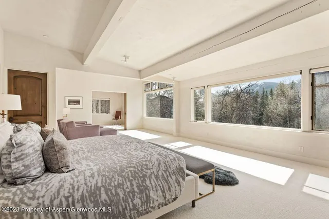 a bed sitting in a spacious bedroom next to a window