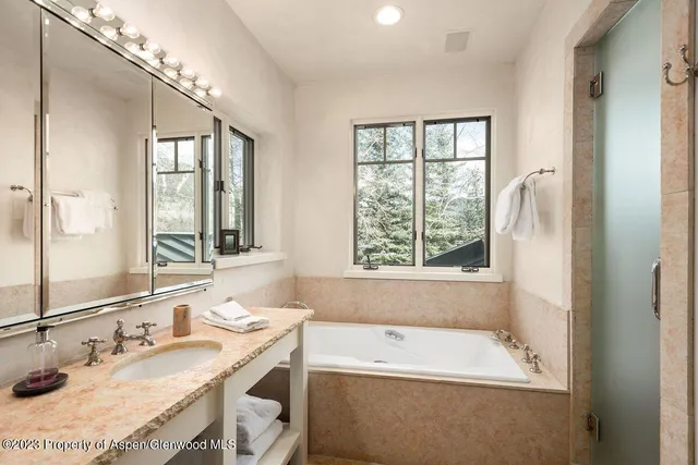 a bathroom with a granite countertop sink a large mirror and a bathtub
