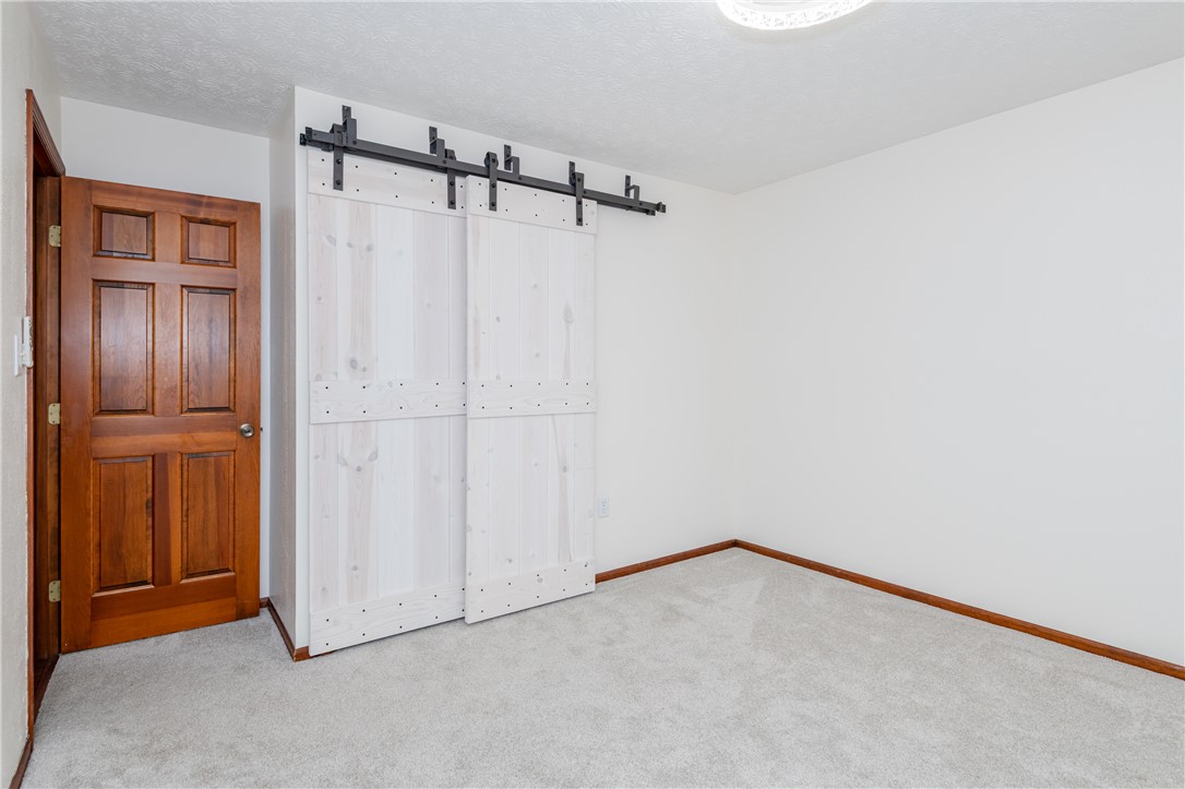 6750 Little Twin Road Germantown, OH 45327 - Photo 26 of 88 Bright room featuring light gray carpet, a classic wooden door, and a modern barn door closet.