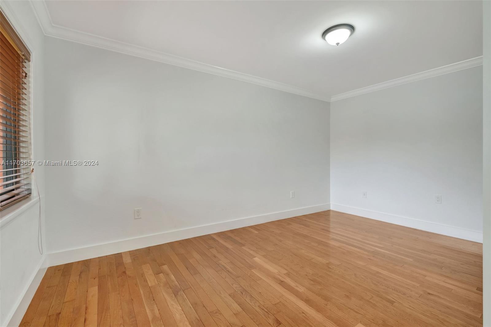 141 Southwest 51st Court, Unit 141 Miami, FL 33134 - Photo 23 of 38 an empty room with wooden floor and windows