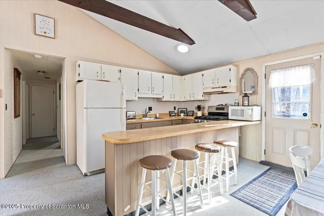 a kitchen with stainless steel appliances granite countertop a refrigerator a stove a sink and white cabinets with wooden floor