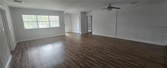a view of an empty room with wooden floor and a window