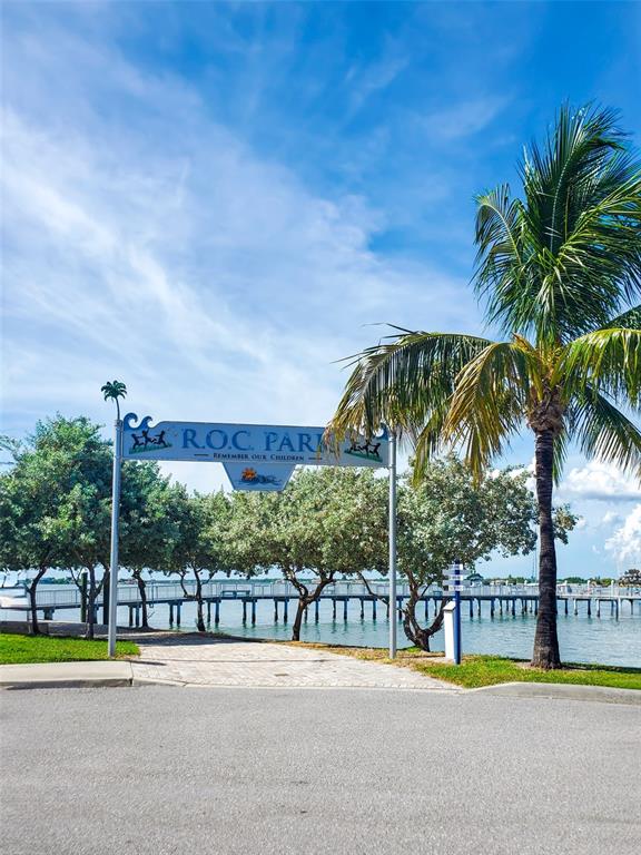 215 Medallion Boulevard, Unit G Madeira Beach, FL 33708 - Photo 24 of 29 a view of a swimming pool with a lawn chairs under palm trees