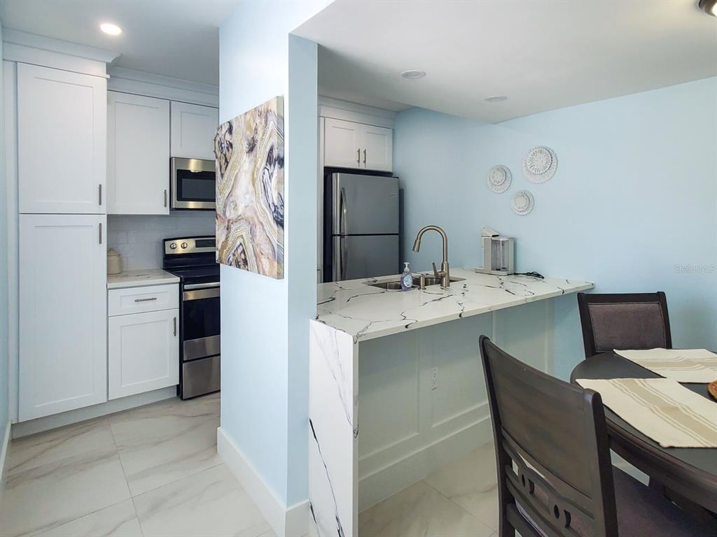215 Medallion Boulevard, Unit G Madeira Beach, FL 33708 - Photo 6 of 29 a kitchen with stainless steel appliances kitchen island a refrigerator sink and cabinets