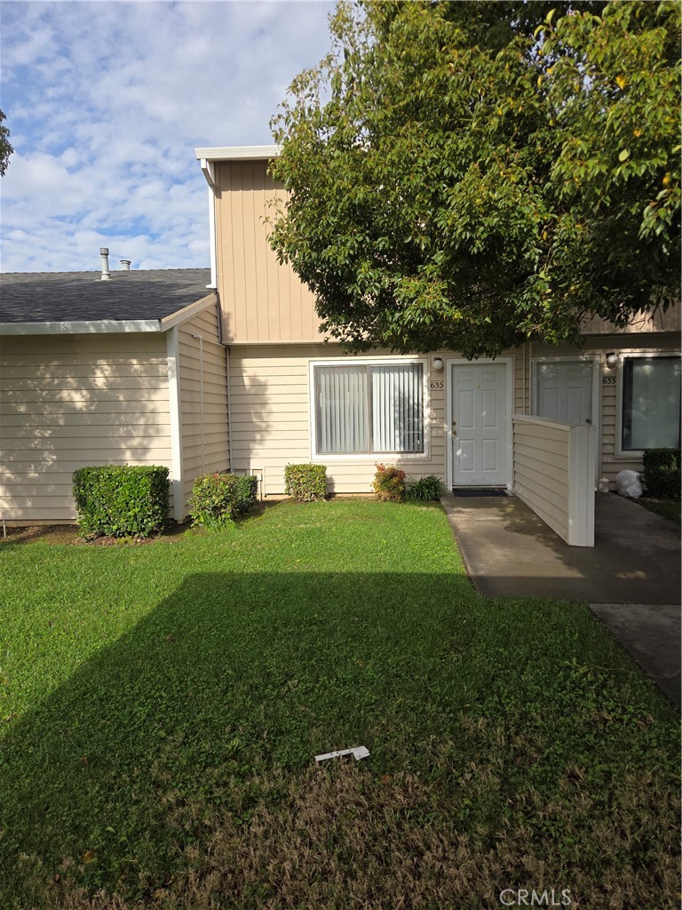 a backyard of a house with plants and large tree