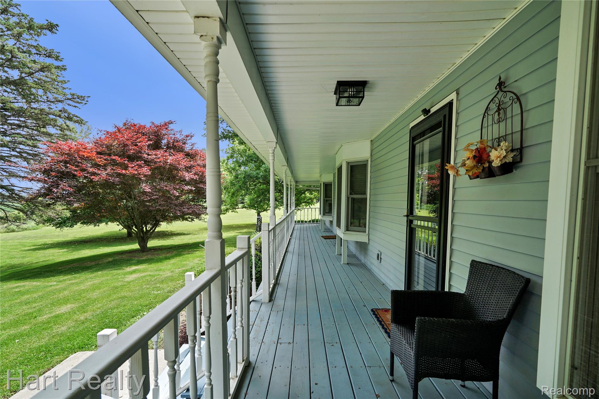 7167 Brown School Road North Branch, MI 48461 - Photo 4 of 51 Expansive covered porch featuring a painted wood floor, white railing, decorative turned columns, and a light blue siding exterior