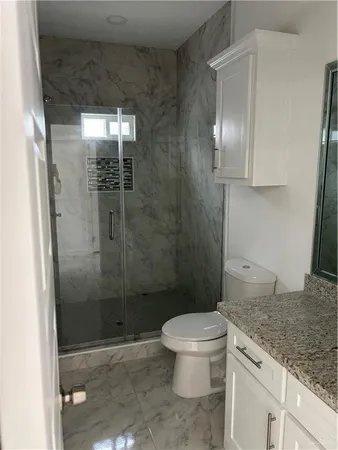 a bathroom with a granite countertop sink a toilet and shower