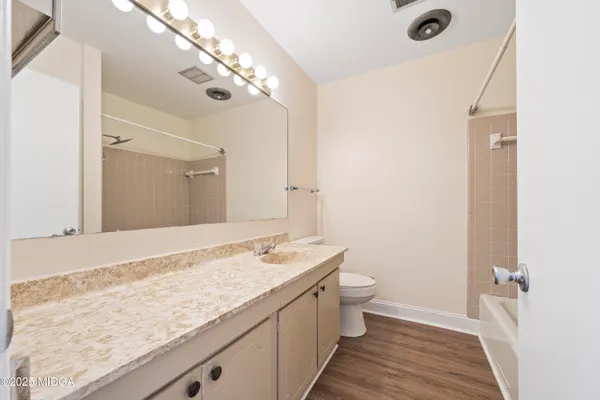 a bathroom with a granite countertop sink a large mirror and toilet