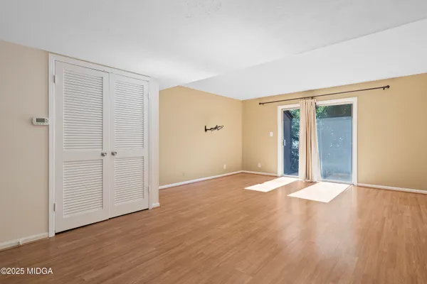 a view of an empty room with wooden floor and closet