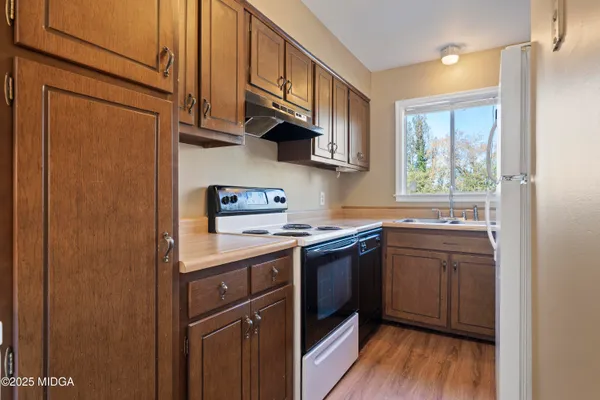 a kitchen with stainless steel appliances granite countertop a sink a stove a refrigerator cabinets and wooden floor