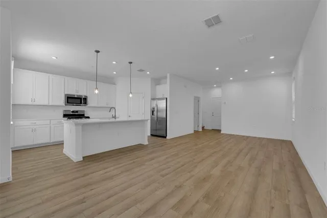 a kitchen with a dining table chairs and wooden floor