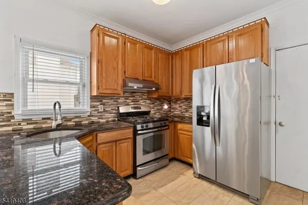 a kitchen with stainless steel appliances granite countertop a refrigerator a sink a stove a washer and dryer