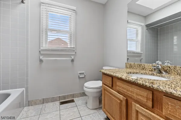 a bathroom with a granite countertop sink a toilet and a mirror