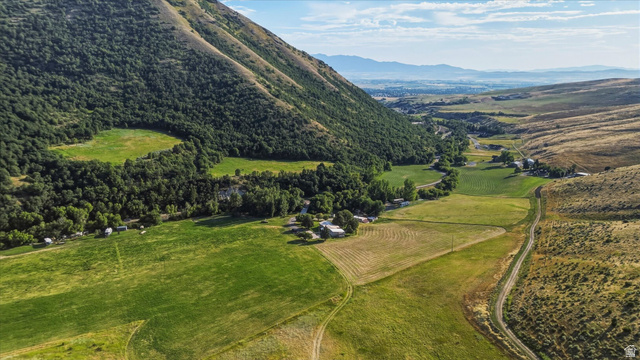 2405 Canyon Road Smithfield, UT 84335 - Photo 1 of 57 Expansive valley property featuring a mountainous backdrop, abundant green fields, scattered trees, and distant structures