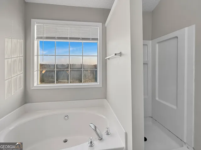 a bathroom with bathtub and next to a window