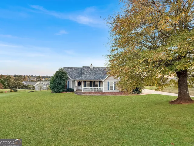 a view of a house with a big yard and large trees