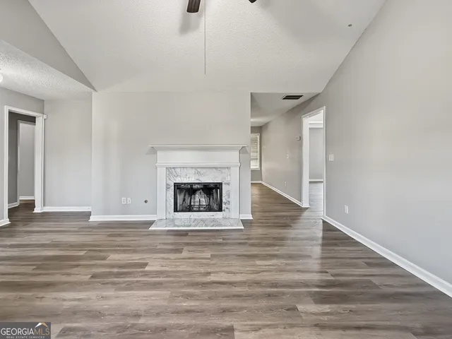 a view of an empty room with wooden floor fireplace and a window