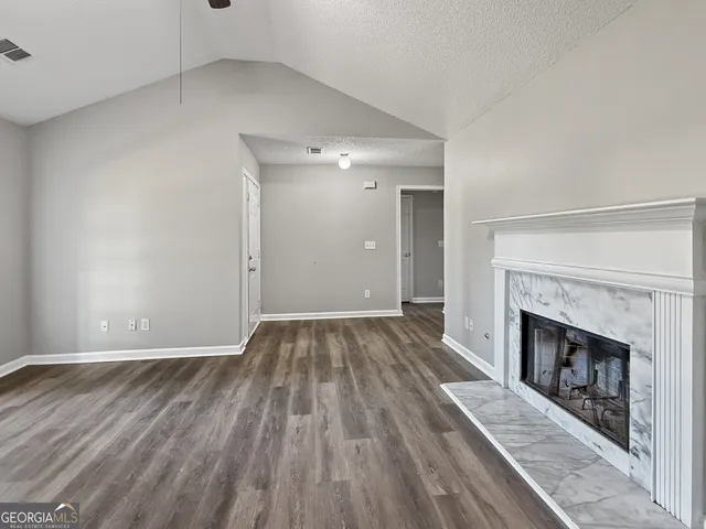 a view of an empty room with wooden floor fireplace and a window