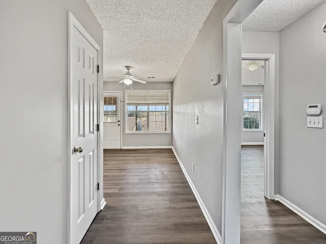 a view of a hallway with wooden floor and a bathroom