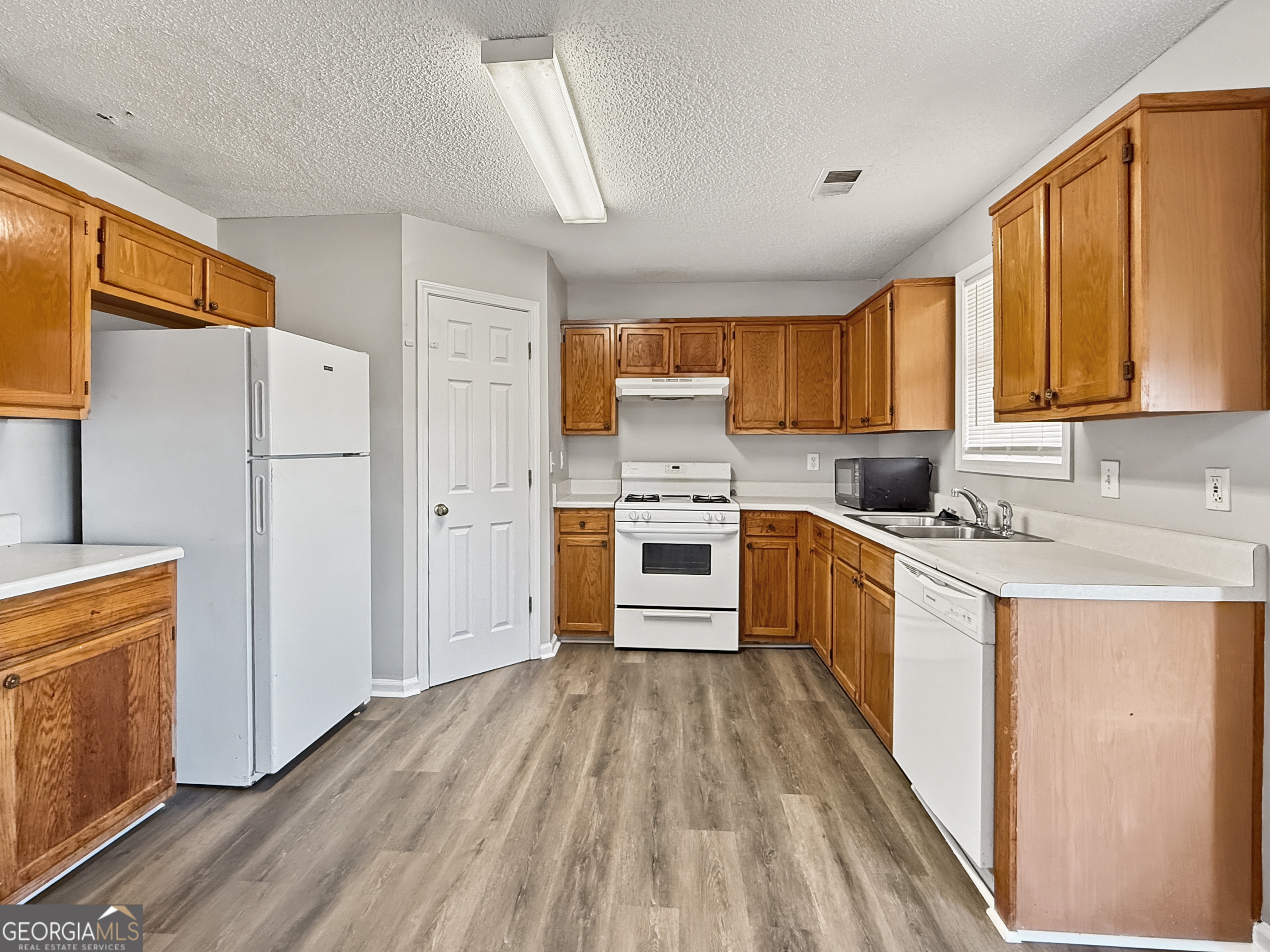 231 Ferguson Avenue Locust Grove, GA 30248 - Photo 9 of 26 a kitchen with a refrigerator a stove top oven a sink dishwasher and wooden cabinets with wooden floor