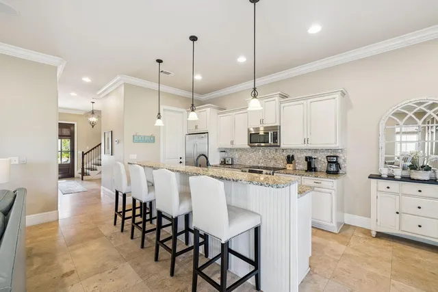 a kitchen with stainless steel appliances kitchen island granite countertop a table chairs sink and cabinets