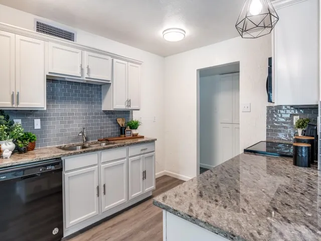 a kitchen with granite countertop a sink a stove cabinets and wooden floor