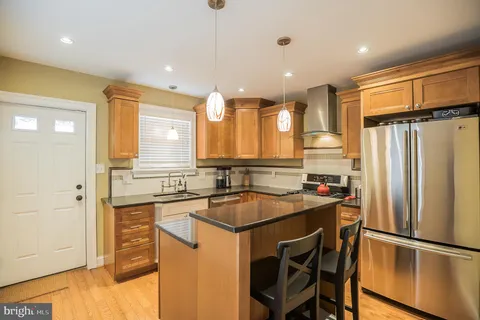 a kitchen with stainless steel appliances granite countertop a refrigerator a sink a stove and a refrigerator