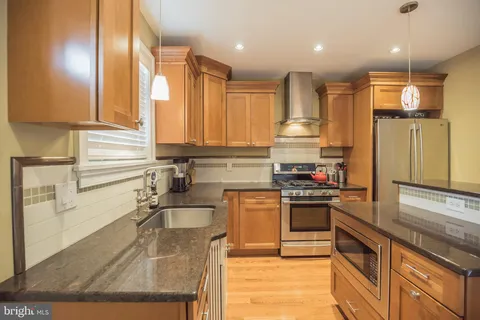 a kitchen with kitchen island granite countertop a sink stainless steel appliances and cabinets