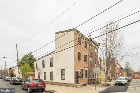 a front view of a building with cars parked on city street