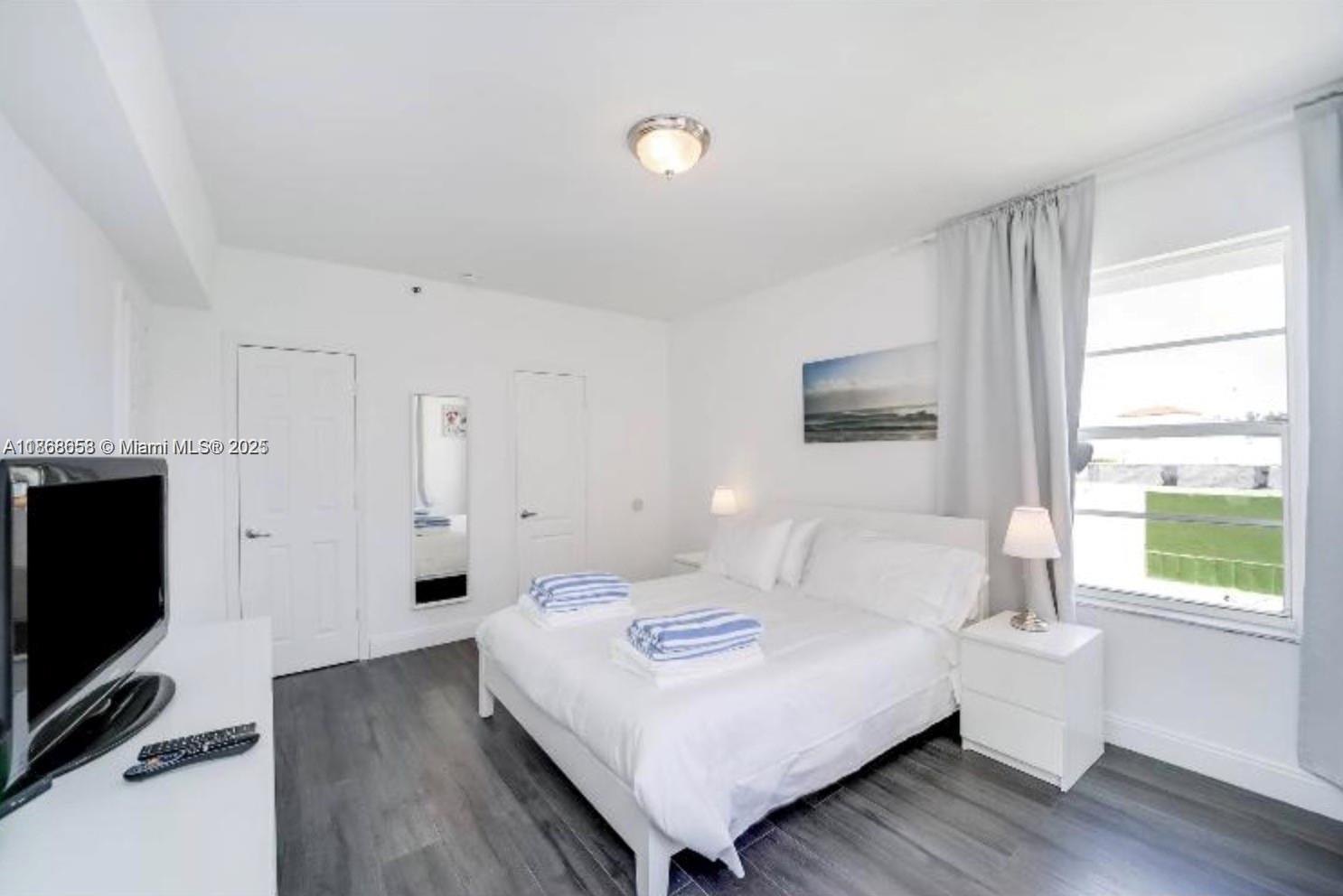 3030 Collins Avenue, Unit 4F Miami Beach, FL 33140 - Photo 4 of 24 a bedroom with a bed and a flat screen tv